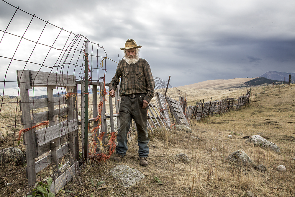 Rancher standing in field next to fence.