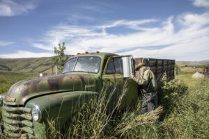 Rancher in the Summer next to vintage farm truck.