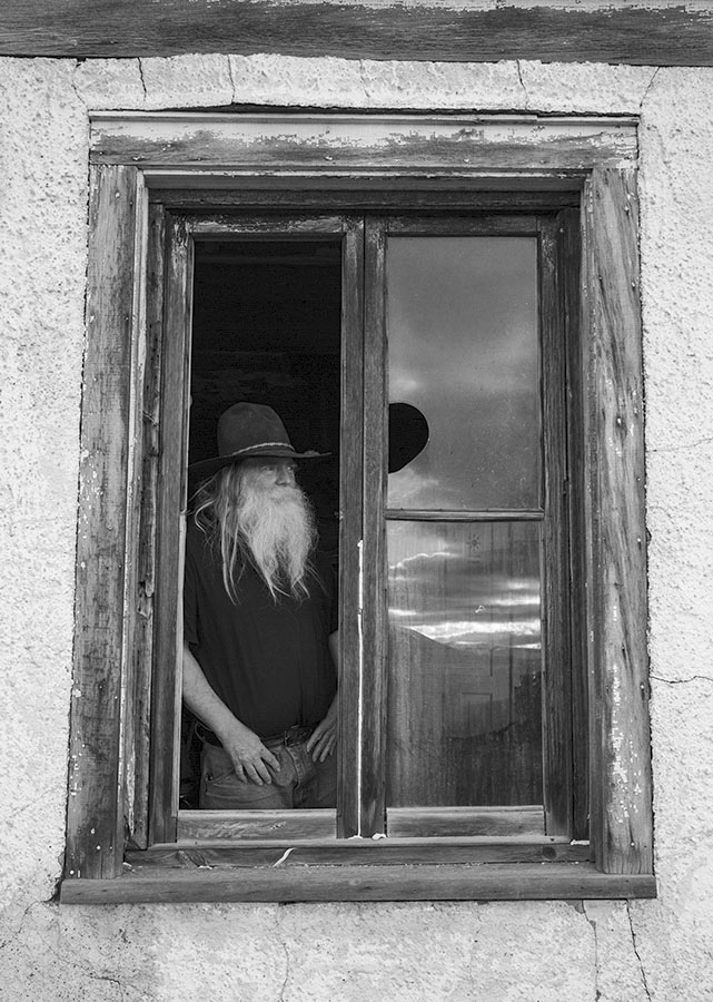Rancher looking out a window onto his property.